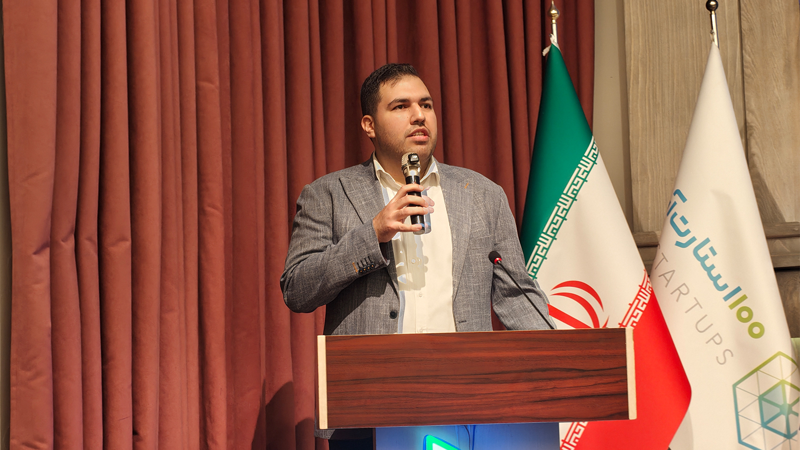 تصویر نزدیک از تندیس و نشان رویداد ۱۰۰ استارتآپ در کنار فضای برگزاری رویداد
